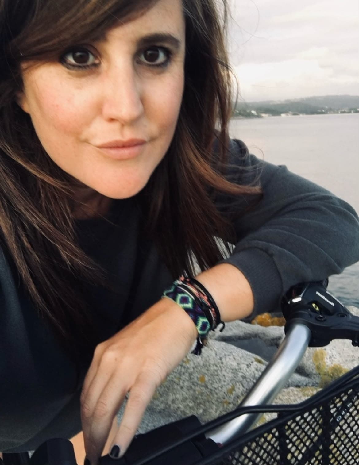 Ivana apoiada no guiador da súa bicicleta, coa ría ao fondo